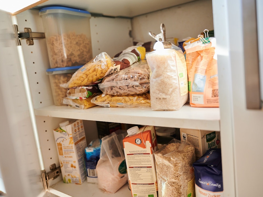 In einem Küchenschrank liegen Vorräte. Nudeln, Zucker, Mehl, Milch und Salz unterschiedlicher Hersteller sind zu sehen.