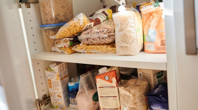 In einem Küchenschrank liegen Vorräte. Nudeln, Zucker, Mehl, Milch und Salz unterschiedlicher Hersteller sind zu sehen.