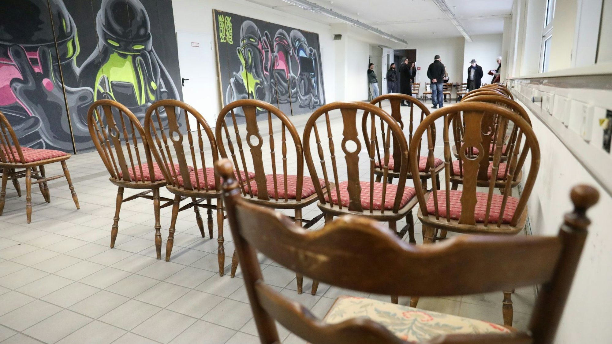 In einer langen Halle stehen schon einige braune Holzstühle für das Konzert bereit. An der Wand lehnen großformatige Streetart-Kunstwerke.