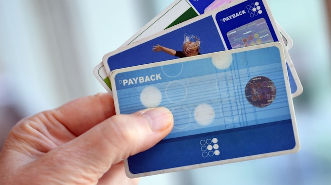 Das Symbolfoto aus dem Jahr 2016 zeigt eine Hand, die drei blaue Payback-Karten hält.