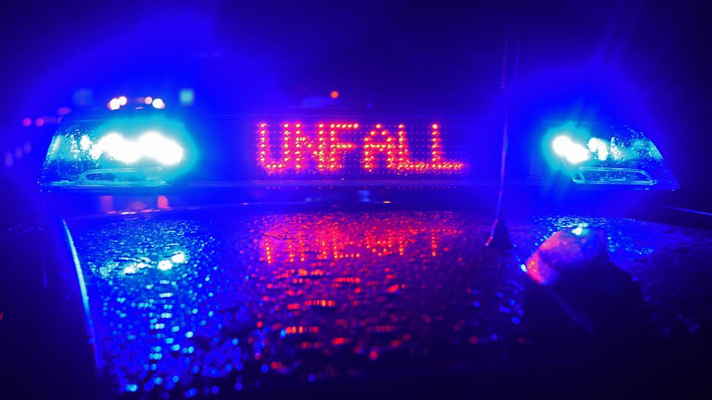 „Unfall“ in roten LED-Leuchtbuchstaben steht zwischen zwei Blaulichtern auf einem Dach eines Polizeiwagens, der auf der A8 am Ort eines Verkehrsunfalls steht.&nbsp;