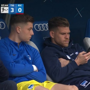 Florian Niederlechner sitzt auf der Bank schaut während des Spiels von Hertha BSC bei der TSG Hoffenheim auf sein Handy.