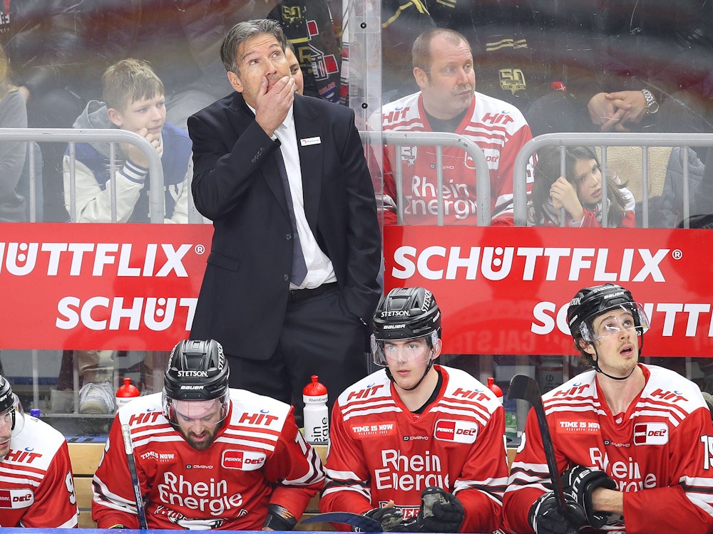 Eishockey-Playoffs in der DEL: Trainer Uwe Krupp, Headcoach der Kölner Haie, steht auf der Spielerbank und schaut angespannt nach oben auf die Anzeigetafel in der Lanxess-Arena.