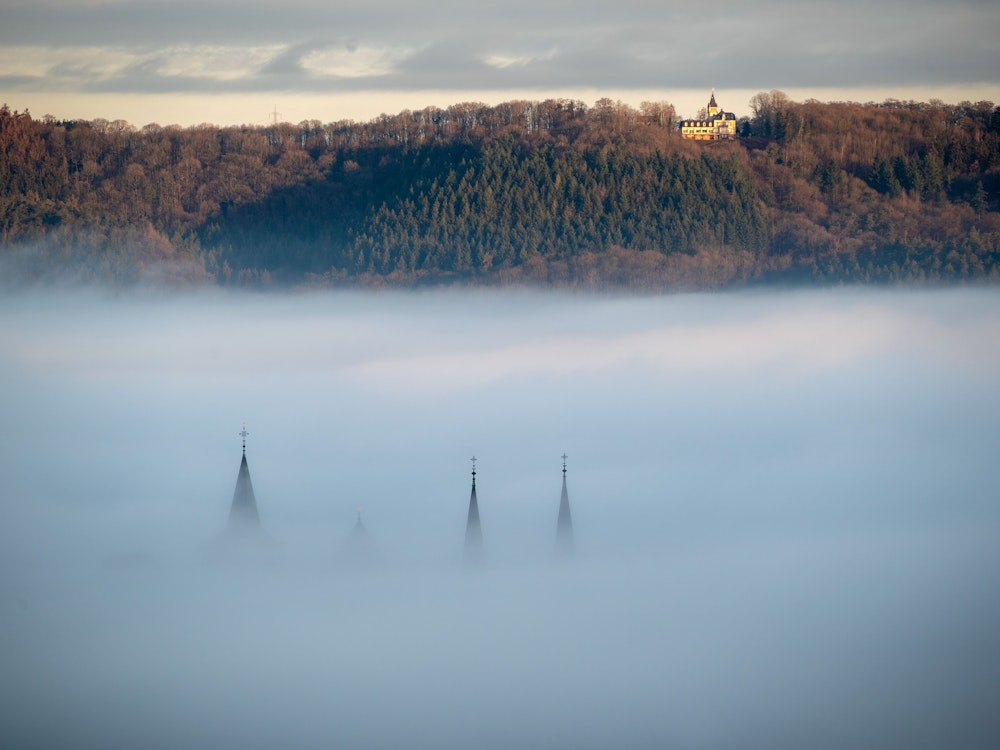 Die Turmspitzen des Trierer Doms und der Liebfrauenkirche ragen aus dem Nebel, der über Teilen der Stadt liegt.