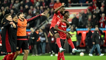 Leverkusens Odilon Kossounou (r) trägt Leverkusens Timothy Fosu-Mensah auf dem Rücken, während sie den Sieg ihrer Mannschaft feiern.