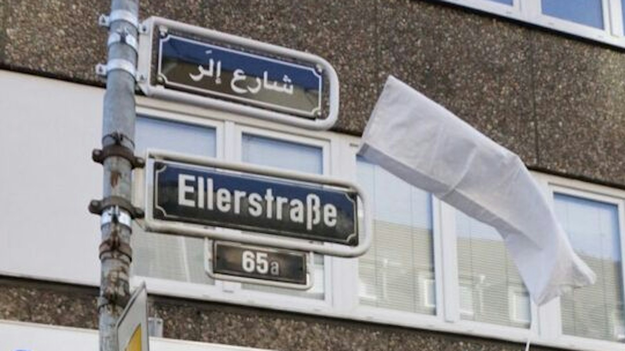 Über dem Straßenschild der Ellerstraße hängt das Schild in arabischer Schrift.