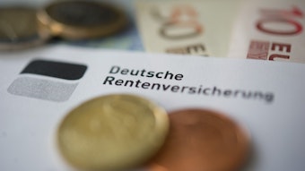 Münzen und Geldscheine liegen neben einem Schreiben mit der Aufschrift «Deutsche Rentenversicherung».