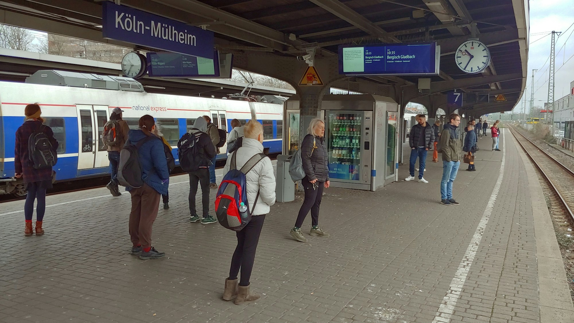 Mehrere Menschen warten am Bahnhof Mülheim auf die Bahn.