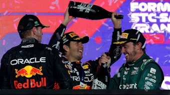 Sergio Perez schüttet Fernando Alonso Champagner über den Kopf, Max Verstappen schaut zu.