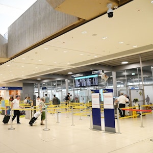 Menschen gehen am Flughafen Köln/Bonn durch die Sicherheits-Gates zu ihren Flügen.