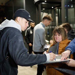Jamal Musiala (l) und Leon Goretzka geben wartenden Fans bei der Anreise des Kaders ins Frankfurter Teamhotel, dem Hotel Melia Frankfurt City, Autogramme.