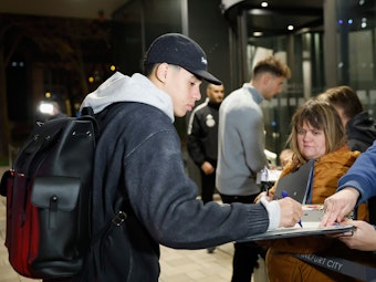 Jamal Musiala (l) und Leon Goretzka geben wartenden Fans bei der Anreise des Kaders ins Frankfurter Teamhotel, dem Hotel Melia Frankfurt City, Autogramme.