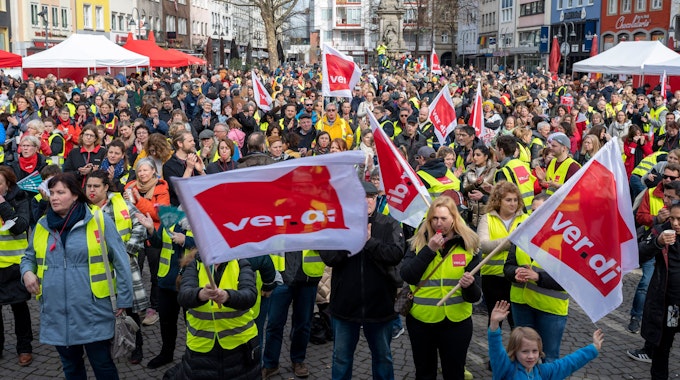 Alter Markt in Köln: Städtische Angestellte demonstrieren vor dem Rathaus. Sie halten große Fahnen der Gewerkschaft Verdi in die Höhe und tragen Warnwesten.