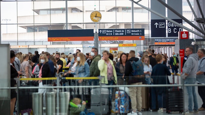 Sommer 2022: Flugreisende warten in einer langen Schlange vor Check-in-Schaltern am Flughafen Köln/Bonn.