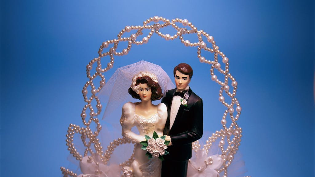 Ein Brautpaar auf einem aufwändig dekorierten Tortenaufsatz