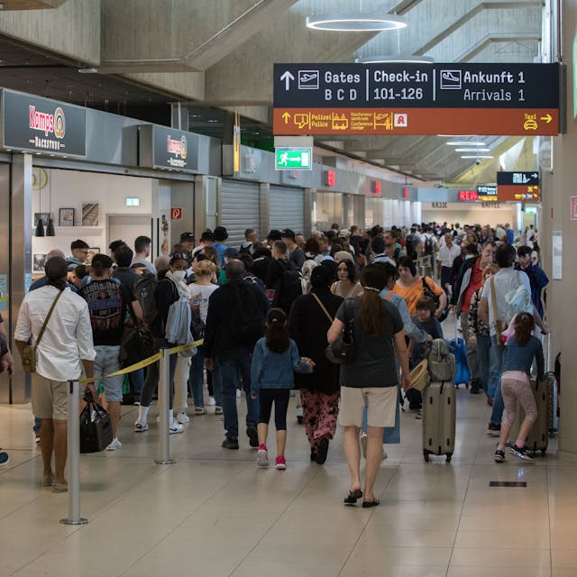 Reisende stehen in den Sommerferien am Flughafen Köln/Bonn in einer Schlange vor der Sicherheitsschleuse.

