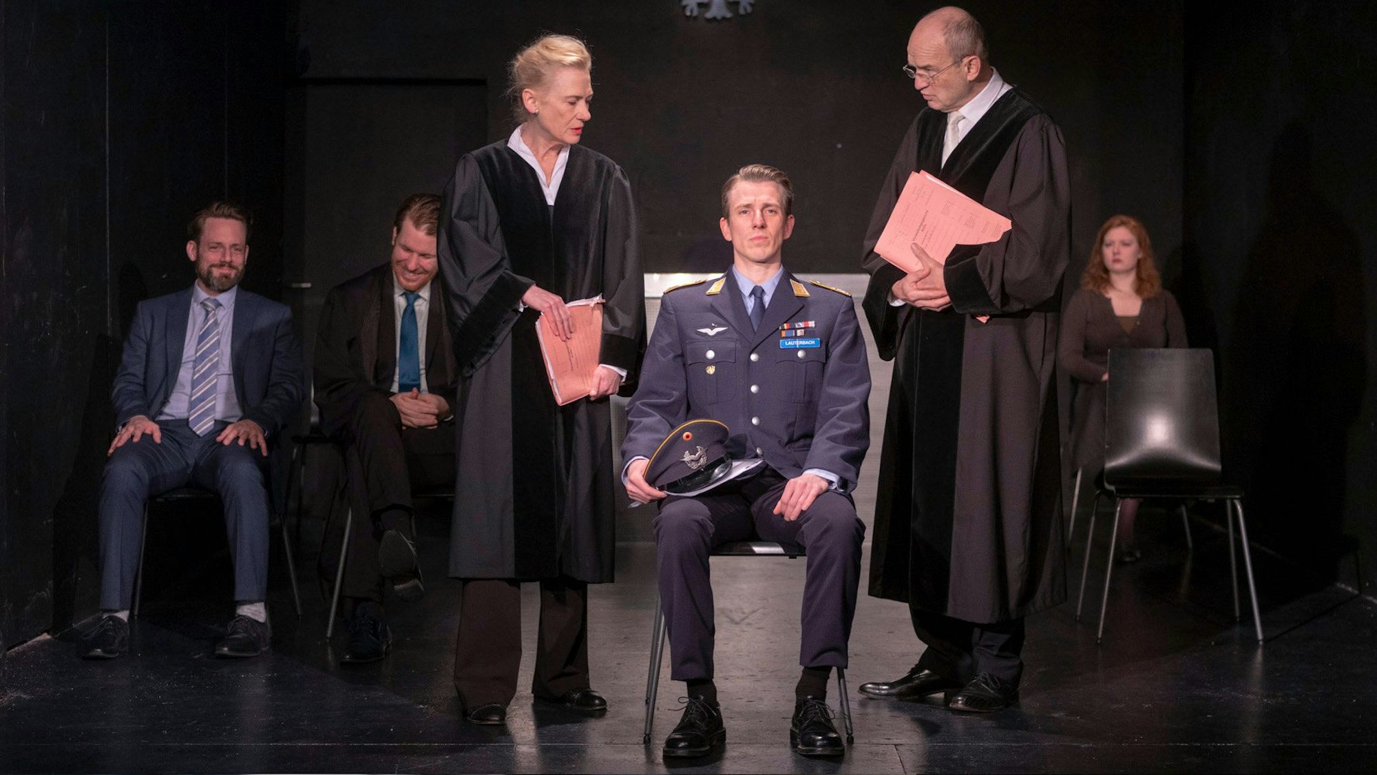 Der Soldat Lars Koch sitzt auf einem Stuhl, rechts und links von ihm die Staatsanwältin und der Richter.