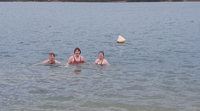 Drei Frauen baden in dem Gewässer.