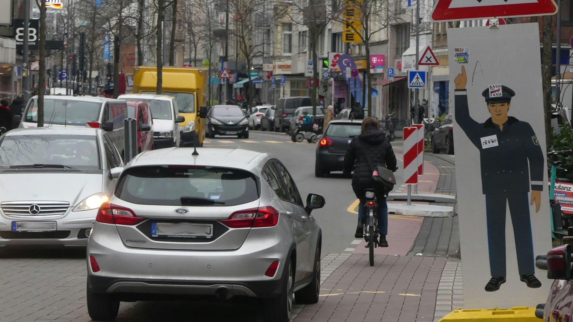 Autos fahren auf der Venloer Straße, auch Fahrräder sind unterwegs, es ist ziemlich voll.
