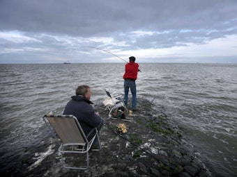 Angler auf einer Mole im Wattenmeer in Friesland (Niederlande).