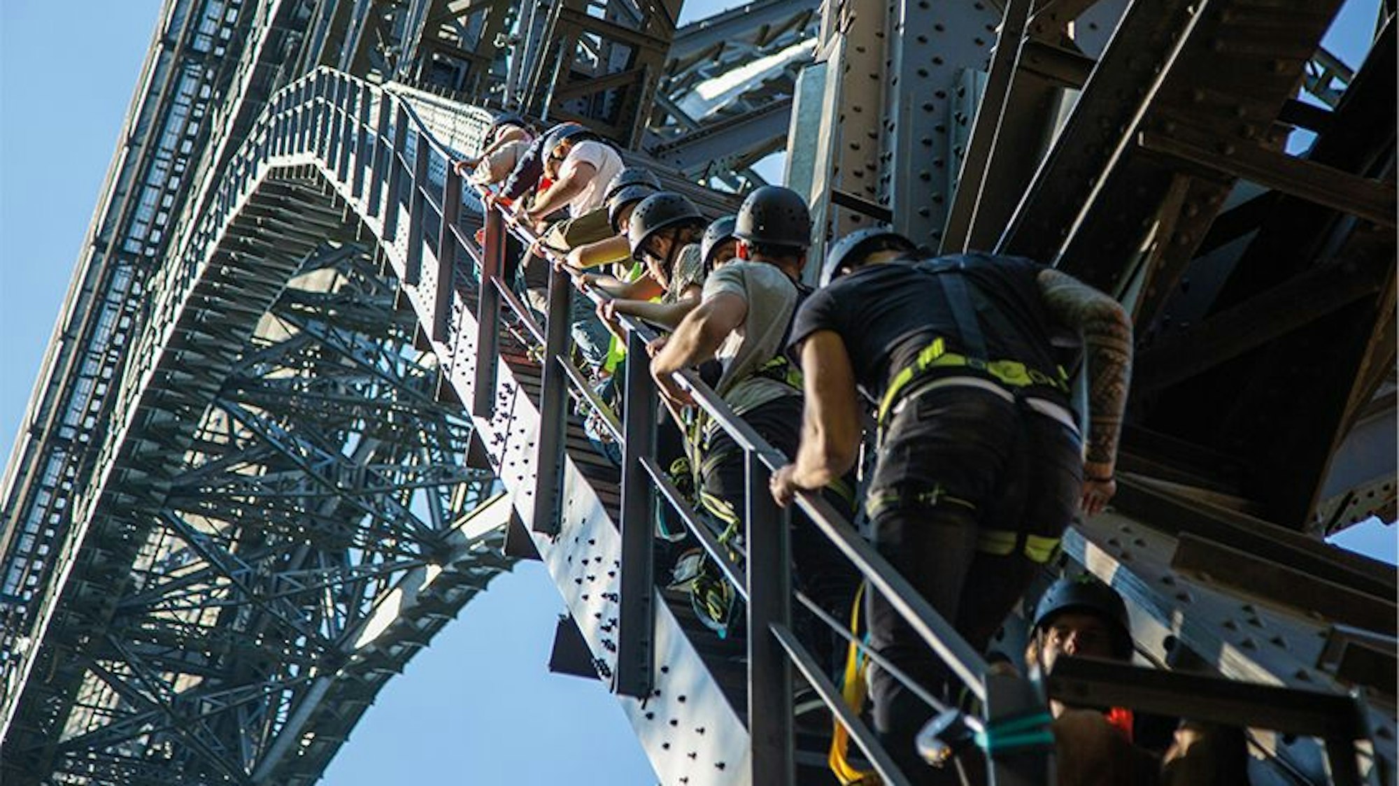 eine Gruppe Kletterer steigt Stufen einer Stahlbrücke hinauf