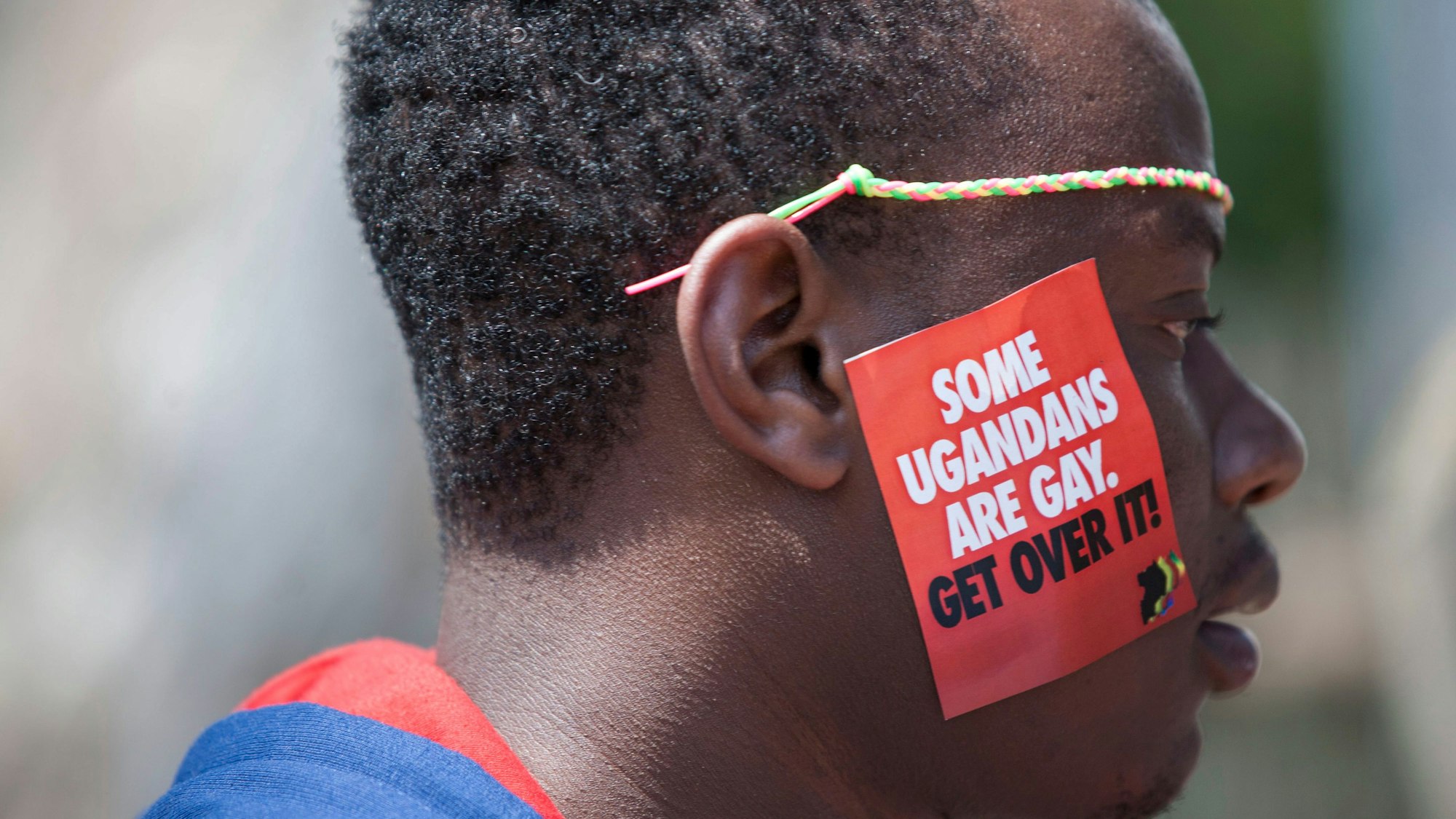 Ein ugandischer Mann trägt einen Aufkleber mit der Aufschrift „Some Ugandans Are Gay. Get Over It“ („Einige Ugander sind schwul. Finde dich damit ab“) während der LGBT-Pride-Feierlichkeiten auf seiner Wange.