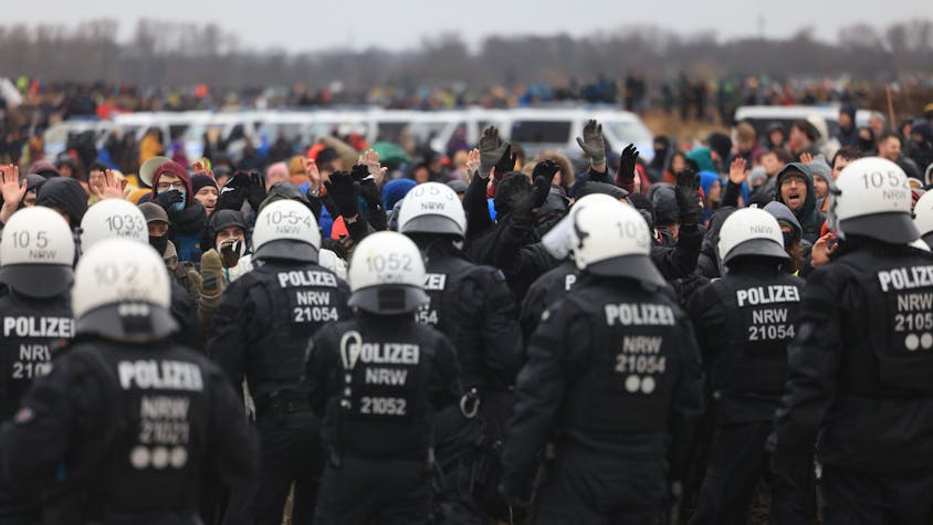 Polizisten und Demonstranten stehen sich bei der Demonstration von Klimaaktivisten am Rande des Braunkohletagebaus bei Lützerath gegenüber.