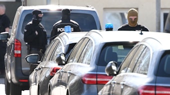 Vermummte Polizisten stehen während der Razzia im „Reichsbürger“-Milieu in Reutlingen an Fahrzeugen.