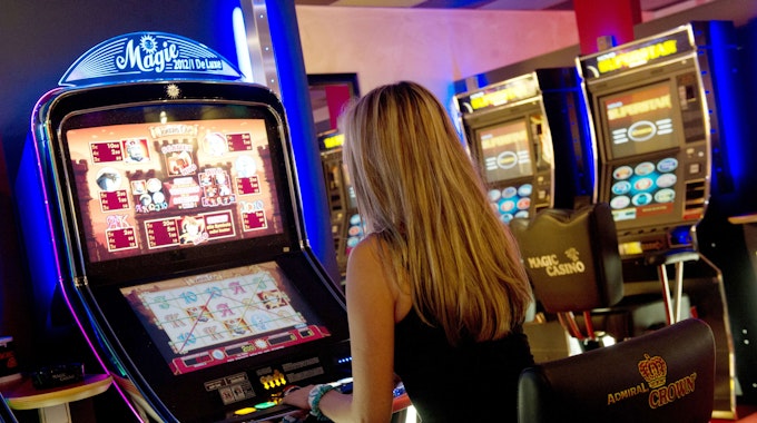 Eine Frau bedient in einer Spielhalle einen Automaten.