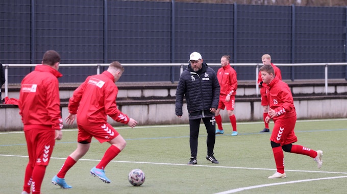 FC-Trainer Steffen Baumgart steht zwischen mehreren Männern, die sich einen Ball zuschießen.