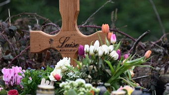 Ein Holzkreuz, zahlreiche Blumen, Kuscheltiere und Kerzen liegen am Tatort.