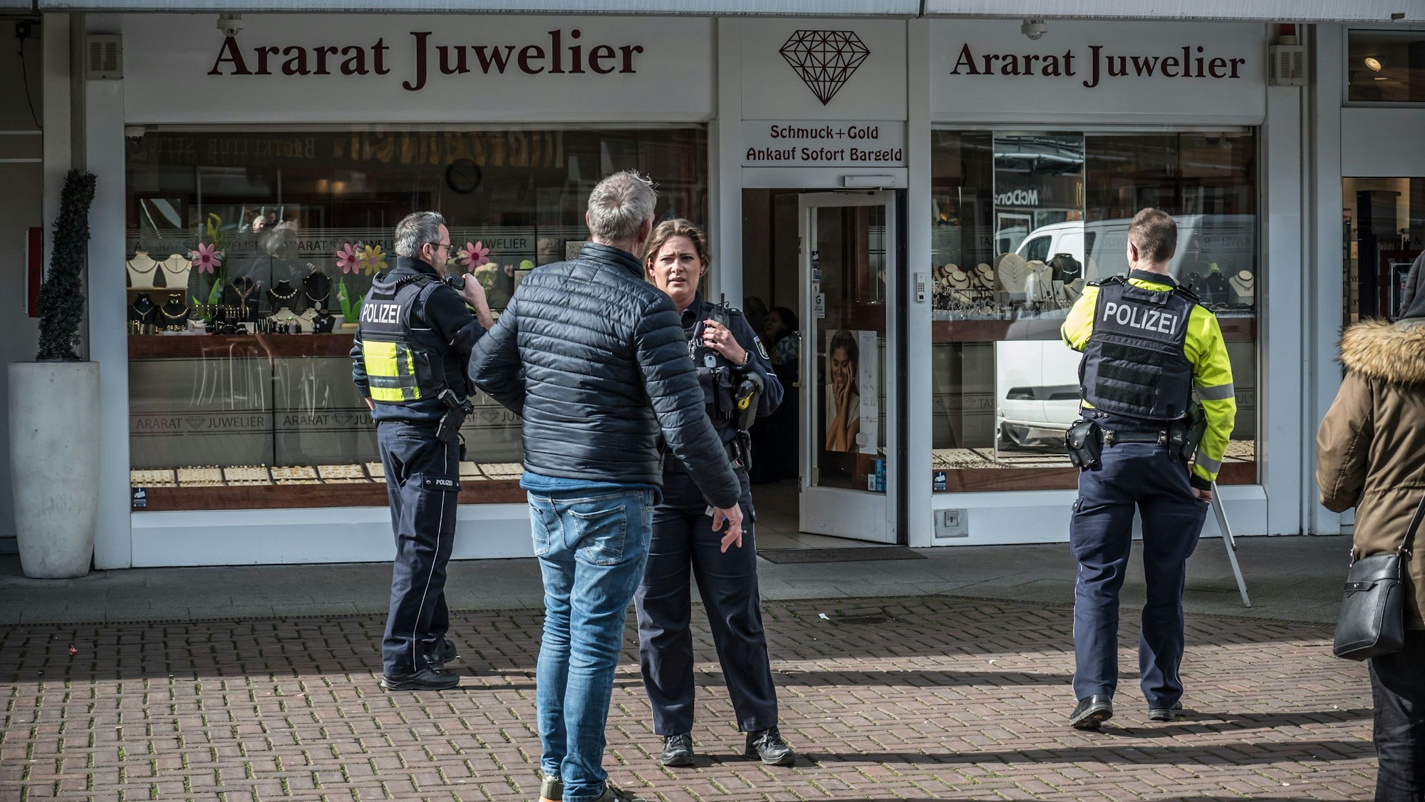 Polizisten und Zivilisten stehen vor dem Juwelier Ararat in Wiesdorfs City B.