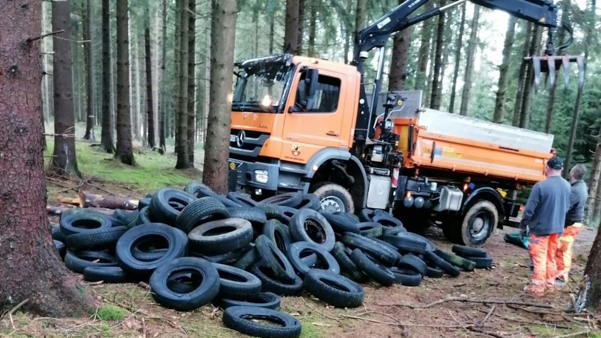 Ein Lkw der Stadt Bad Münstereifel steht im Wald und lädt illegal entsorgte Altreifen auf.