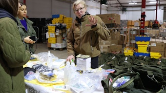 Die Ukrainische Notfallärztin Tayra besucht Spendenlager des Blau-Gelben Kreuzes. Sie inspiziert zwei Medizin-Rucksäcke, deren Inhalt auf dem Tisch ausgebreitet ist.