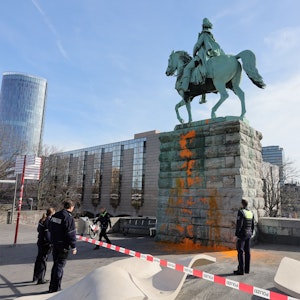 Einsatzkräfte der Polizei begutachten am 16. März 2023 die Farbattacke am Reiterdenkmal an der Hohenzollernbrücke.