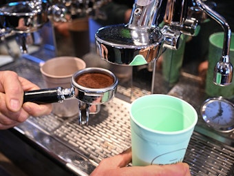 Ein Café-Mitarbeiter bereitet einen Kaffee zu. In Köln beziehungsweise NRW will eine neue Kaffee-Kette den Markt aufmischen.