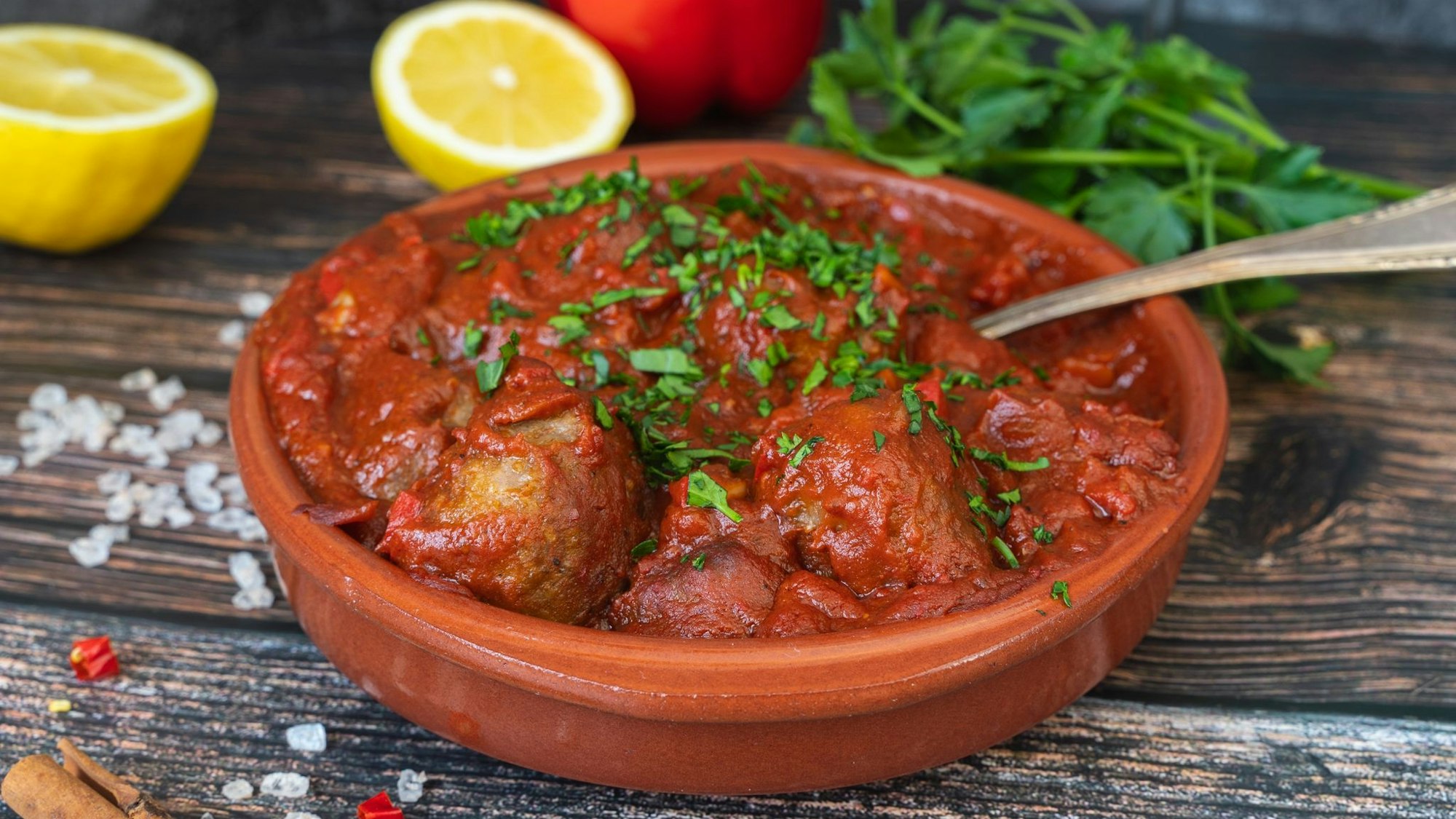 Albondigas (spanische Fleischbällchen in Tomatensoße) serviert in einer Terakottaschüssel.