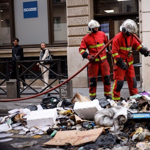 Frankreich, Paris: Feuerwehrleute kontrollieren die Überreste eines Müllfeuers von den gestrigen Protesten gegen das Rentengesetz.