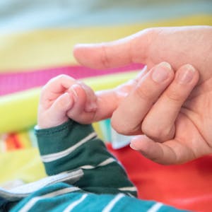 Ein Baby nimmt die Hand eines Erwachsenen.
