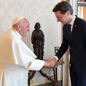 Hendrik Wüst und Papst Franziskus schüttel sich lächelnd die Hände.