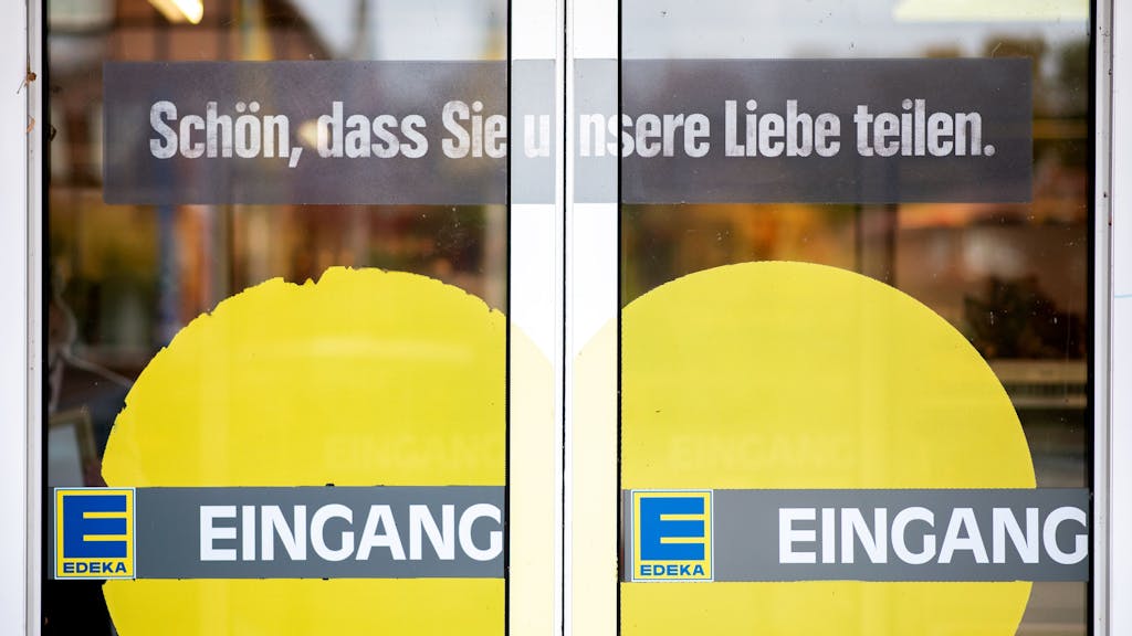 Das Symbolfoto aus dem Jahr 2020 zeigt die Eingangstüren einer Edeka-Filiale. Auf das Glas sind ein gelbes Herz, das Edeka-Logo sowie die Schriftzüge „Eingang“ und „Schön, dass Sie unsere Liebe teilen.“ gedruckt.