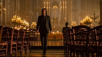 Keanu Reeves als John Wick geht in einer Szene des Spielfilms „John Wick: Kapitel 4“ durch eine von Kerzen beleuchtete Kirche.