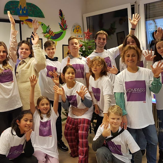 Kinder und Jugendliche tragen ein weißes T-Shirt mit dem lila-farbigen Logo des „Kompass“-Projekts, im Rahmen dessen der Kölner Verein Phoenix Kreativ-Kurse angeboten hat.