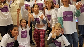 Kinder und Jugendliche tragen ein weißes T-Shirt mit dem lila-farbigen Logo des „Kompass“-Projekts, im Rahmen dessen der Kölner Verein Phoenix Kreativ-Kurse angeboten hat.