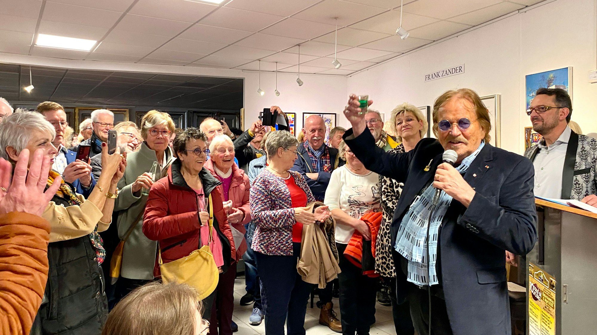 Das Bild zeigt Sänger und Künstler Frank Zander in der Galerie Wehr vor einem begeisterten Publikum.