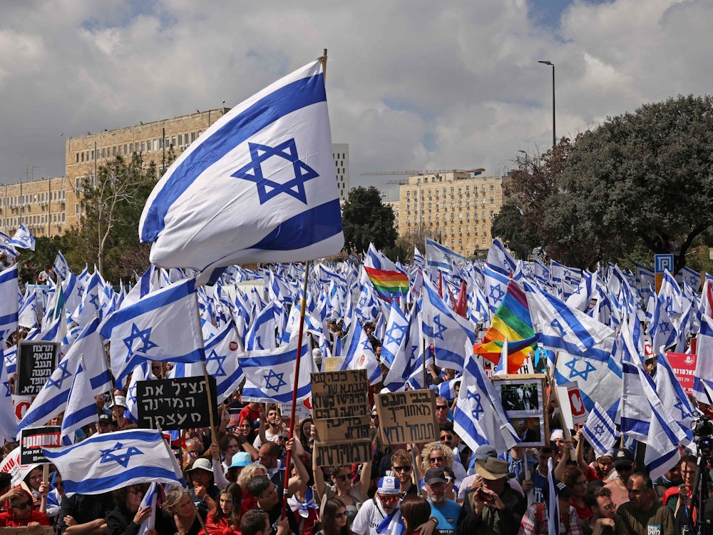 Demonstranten und Demonstrantinnen versammeln sich vor dem israelischen Parlament in Jerusalem mit Flaggen und Schildern, um zu demonstrieren.