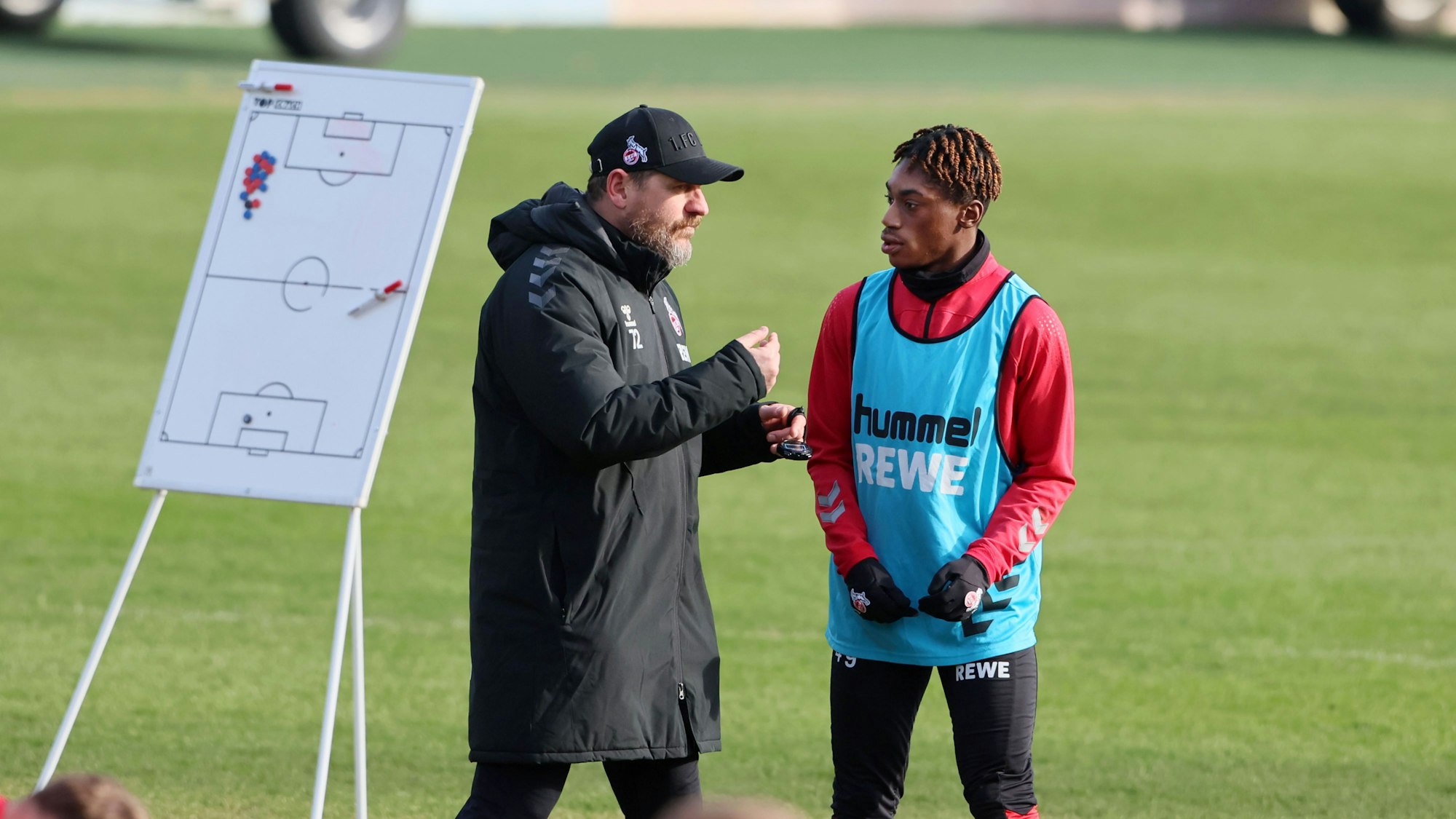 Steffen Baumgart spricht im Training mit Nachwuchsstürmer Justin Diehl. Im Hintergrund ist eine Taktiktafel zu sehen.