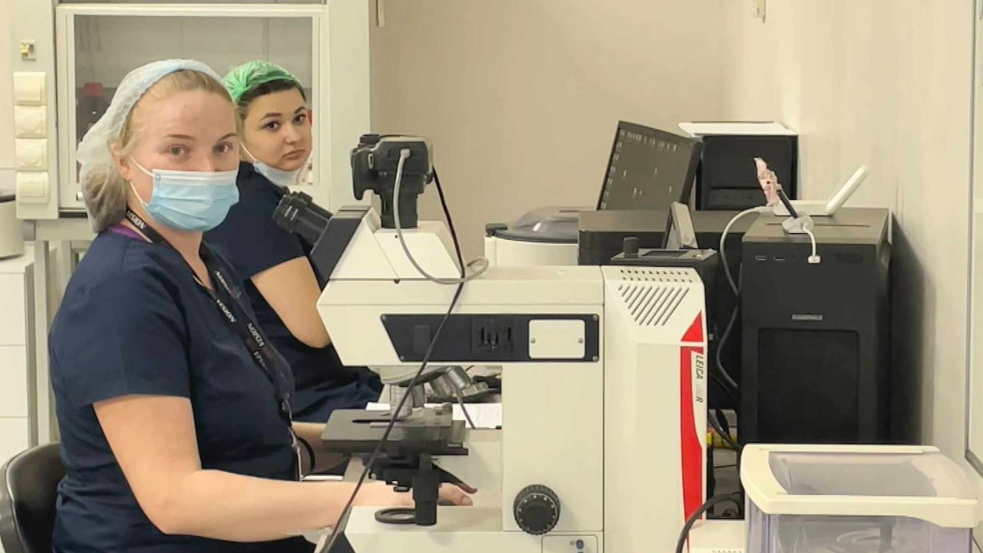 Zwei Frauen mit Mundschutz sitzen vor einem Mikroskop in der Firmenzentrale der Biotexcom-Zentrale in Kiew
