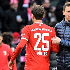 Thomas Müller und Trainer Julian Nagelsmann vom FC Bayern München stehen nach dem Spiel auf dem Platz und klatschen ab.