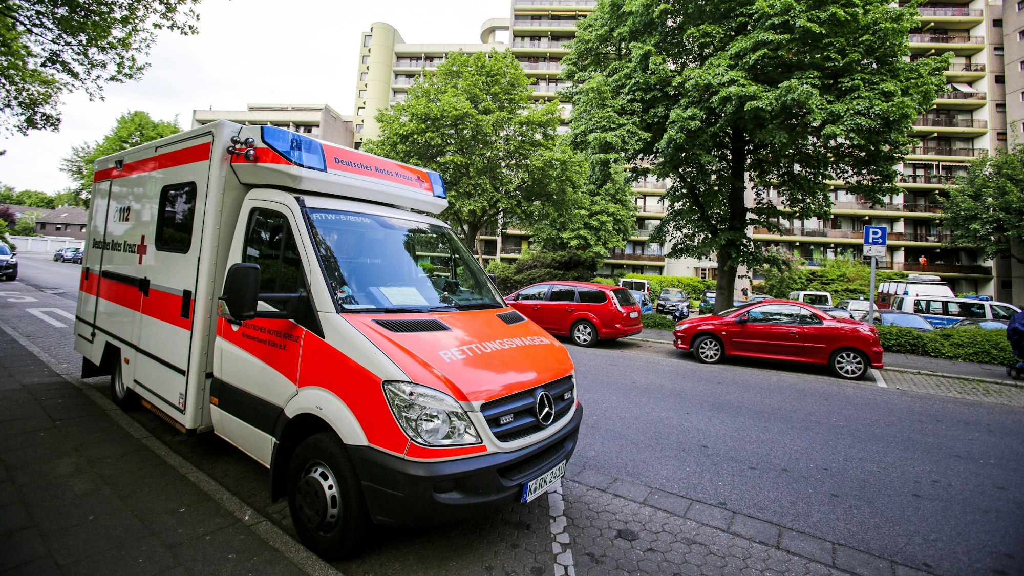 Ein Rettungswagen (RTW) des Deutschen Roten Kreuz (DRK) steht vor einem Wohnhaus in Köln.